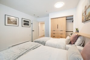A bedroom with two beds, a wardrobe, and a door leading to another room. - Free Parking | Blueberry Hill | Apple TV | Wifi (Whistler)
