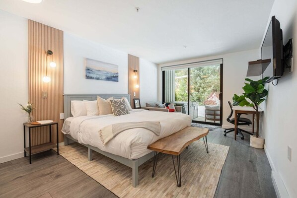 A modern bedroom with a large bed, bedside tables, a desk, and a TV. - Free Parking | Blueberry Hill | Apple TV | Wifi (Whistler)