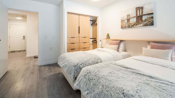 A bedroom with two beds, a wardrobe, a painting, and a hallway. - Free Parking | Private hot tub | Blueberry Hill (Whistler)