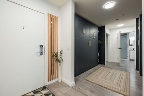 A hallway with a white door, a wooden slat partition, a dark-colored wardrobe, and a patterned rug. - Free Parking | Blueberry Hill | Apple TV | Wifi (Whistler)