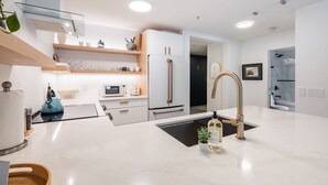 A modern kitchen with white cabinetry, a stainless steel sink, and a built-in oven. - Free Parking | Private hot tub | Blueberry Hill (Whistler)