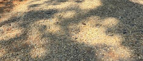 A gravel driveway leading to a wooden deck with a black building in the background.