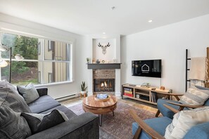 Ein modernes Wohnzimmer mit Kamin, Fernseher und bequemen Sitzmöglichkeiten.