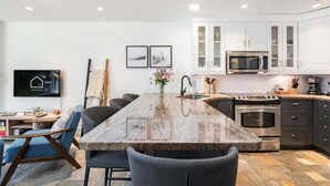 Eine moderne Küche mit Granit Arbeitsplatten, Edelstahlgeräten und einem Essbereich mit einem langen Tisch und Stühlen.