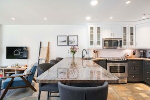 Eine moderne Küche mit Granit Arbeitsplatten, Edelstahlgeräten und einem Essbereich mit einem langen Tisch und Stühlen.
