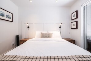 Ein Schlafzimmer mit einem großen Bett, zwei Nachttischen, einem Kopfteil und Wandleuchten.