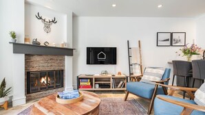 Ein modernes Wohnzimmer mit Kamin, Wandfernseher und gemütlicher Sitzecke.