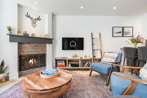 Ein modernes Wohnzimmer mit Kamin, Wandfernseher und gemütlicher Sitzecke.