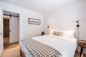 Ein Schlafzimmer mit einem großen Bett, einem gerahmten Bild an der Wand und einer Tür zu einem Badezimmer.