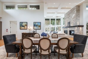 A spacious dining area with a large wooden table and six chairs, a fireplace, and a stone accent wall. - Ultimate Secluded Chalet | Private hot tub (Whistler)