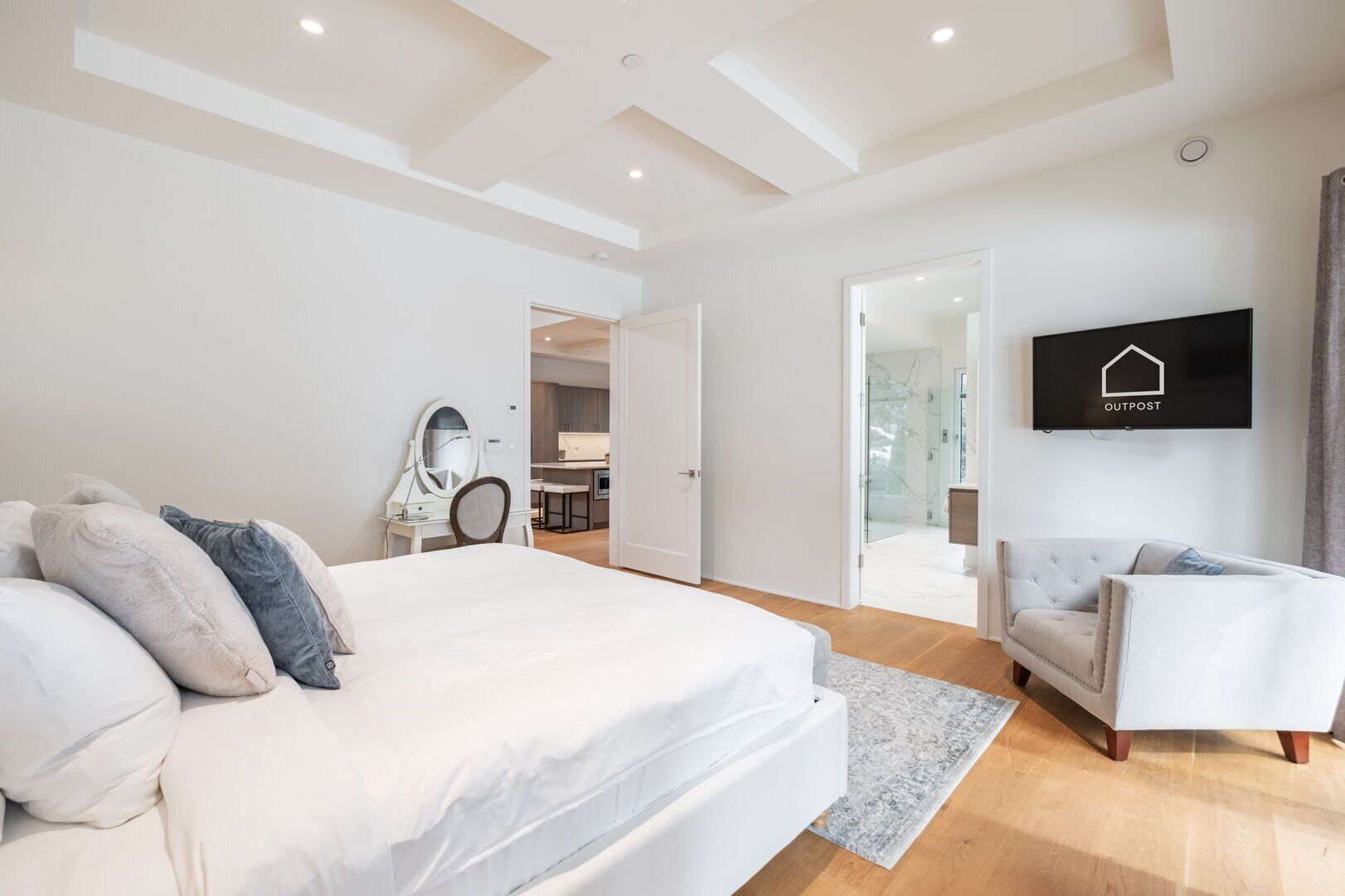 Een moderne slaapkamer met een groot bed, een aan de muur bevestigde televisie en een aparte zithoek.