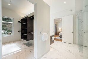 Een moderne badkamer met een inloopdouche, een ingebouwde plankkast van donker hout en een glazen douchecabine.