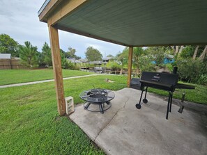 Eine überdachte Terrasse mit Grill und rundem Tisch.