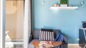 Un soggiorno con un divano, un tavolino da caffè con riviste, una parete blu e una finestra con tenda.