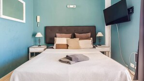 Una camera d'albergo con un letto, due comodini, una televisione a schermo piatto montata a parete e una finestra.