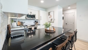 A modern kitchen with a large island, stainless steel appliances, and a minimalist design. - Ski-in/out | Complex pool, hot tub & BBQ | WIFI (Whistler)