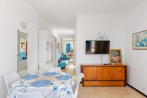 A modern living room with a dining table, a TV, and a wooden cabinet. - 2 Bedroom Apartment with Seaview (Costa Adeje-Playas De Fañabe)
