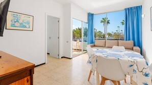 A room with a bed, a table, a TV, and a balcony with a view. - 2 Bedroom Apartment with Seaview (Costa Adeje-Playas De Fañabe)