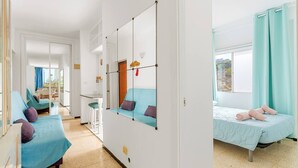 A room with two beds, a dining area, and a large window. - 2 Bedroom Apartment with Seaview (Costa Adeje-Playas De Fañabe)