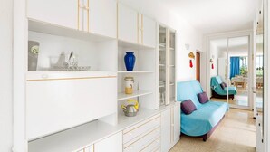 A modern living room with a sofa, a coffee table, and a bookshelf with decorative items. - 2 Bedroom Apartment with Seaview (Costa Adeje-Playas De Fañabe)