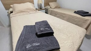 Une chambre d’hôtel avec deux lits, chacun doté d’une tête de lit, d’une table de chevet avec une lampe et d’une serviette pliée posée sur le lit.
