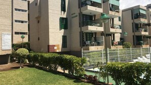 Un immeuble à plusieurs étages doté de balcons, d’une piscine entourée d’une clôture et d’une enseigne indiquant « CASADON ».