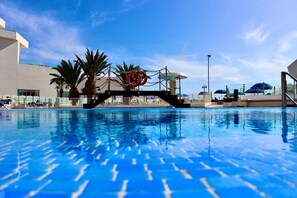 Ein Schwimmbecken mit klarem, blauem Wasser, Palmen und einem Rettungsschwimmerstand.