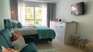 Een slaapkamer met een bed, een bank, een televisie, een bureau en een raam.