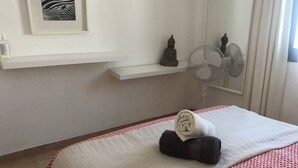A hotel room with a bed, a wall-mounted shelf with a statue, a fan, and a framed picture. - Playa Troya Apartment at the beach (Costa Adeje)