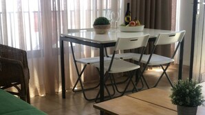A room with a bed, a dining table with chairs, a small potted plant, and a bottle of wine on the table. - Playa Troya Apartment at the beach (Costa Adeje)