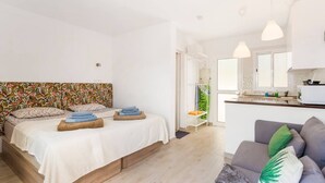 Una camera da letto con un letto, comodini, un divano grigio e un bagno con doccia.