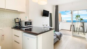 Una cucina moderna con forno a microonde, macchina del caffè e bicchieri da vino sul bancone.