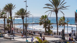 A coastal promenade with palm trees, a beach, and a clear sky. - Beachfront Studio Las Americas (Costa Adeje)