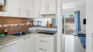 A modern kitchen with white cabinets, a stainless steel sink, and a black countertop. - Beachfront Studio Las Americas (Costa Adeje)