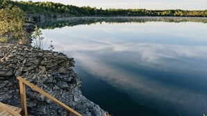 A calm lake with a stone platform and wooden steps leading to a wooden deck. - Sorrel Tent | Canvas Tent with Lake Access (Kirkfield)