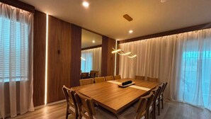 Een eetgedeelte met een houten tafel en stoelen, een grote spiegel en een moderne lamp.