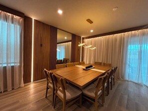 A dining area with a wooden table and chairs, a large mirror, and a modern light fixture. - 8 BD/ 6 BA/ Windsor Cay (16079 CC) (Clermont)