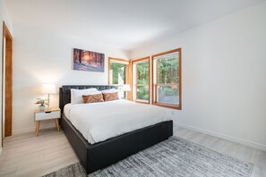 Ein Schlafzimmer mit einem großen Bett, einem Nachttisch mit Lampe und einem Bild über dem Bett.