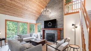 A modern living room with a fireplace, large windows, and a cozy seating area. - Excellent Ski-in/out | Complex hot tub | BBQ (Whistler)