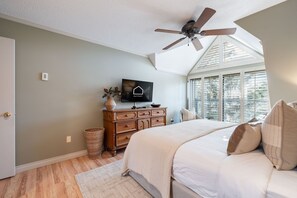 A bedroom with a bed, a ceiling fan, a dresser, a television, and a window with blinds. - Townhome Near Blackcomb Lift | BBQ | Free Parking (Whistler)