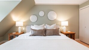 Een slaapkamer met een groot bed, twee nachtkastjes met lampen, en een kledingkast.