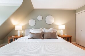 A bedroom with a large bed, two bedside tables with lamps, and a wardrobe. - Townhome Near Blackcomb Lift | BBQ | Free Parking (Whistler)