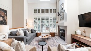 Een moderne woonkamer met een grijze bank, een ronde salontafel en een open haard.