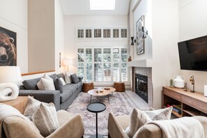 A modern living room with a grey sofa, a round coffee table, and a fireplace. - Townhome Near Blackcomb Lift | BBQ | Free Parking (Whistler)