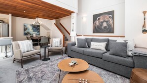 Een moderne woonkamer met een grijze bank, een bijzettafeltje en een schilderij van een beer aan de muur.