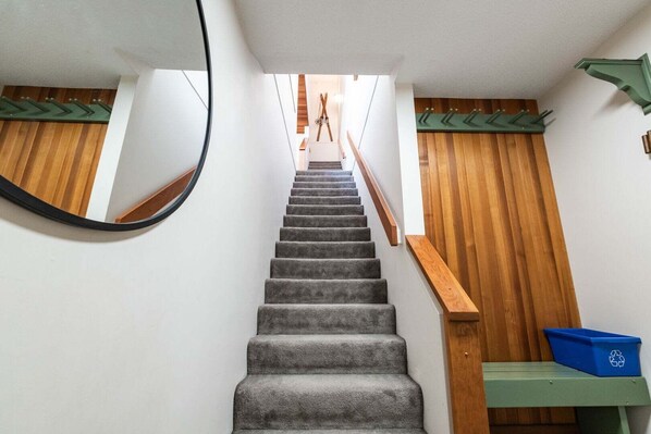 A staircase with grey carpet, wooden handrails, and a blue recycling bin. - Townhome Near Blackcomb Lift | BBQ | Free Parking (Whistler)