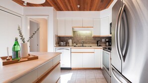 Een moderne keuken met witte kastjes, roestvrijstalen apparatuur en een houten aanrecht.