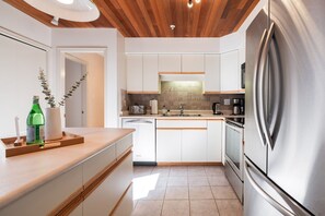 A modern kitchen with white cabinets, stainless steel appliances, and a wooden countertop. - Townhome Near Blackcomb Lift | BBQ | Free Parking (Whistler)