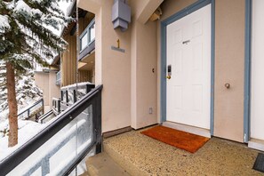 A hotel entrance with a snow-covered exterior, a red doormat, and a blue-framed door. - Townhome Near Blackcomb Lift | BBQ | Free Parking (Whistler)