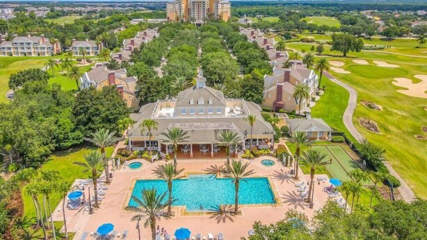 Een resort met een centraal gelegen zwembad, diverse gastenkamers en een golfbaan op de achtergrond.